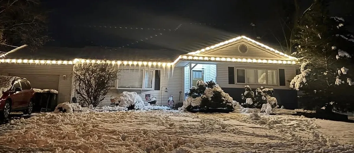 A house outlined in white C9 Christmas lights in the snow in Ocean County, New Jersey
